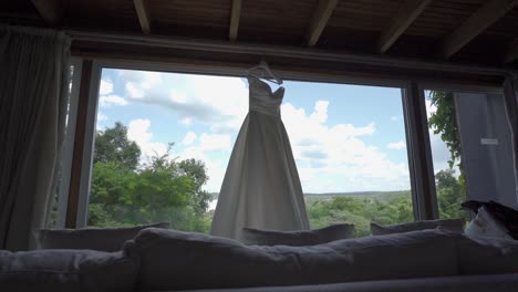beautiful long white wedding dress hanging in the open window of the hotel room overlooking the iguazu falls