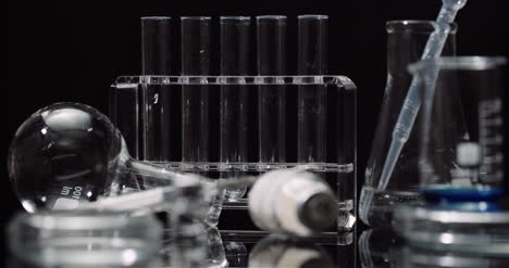 equipo de laboratorio: jeringas y tubos de ensayo de medicamentos y matraces girando sobre fondo negro 8