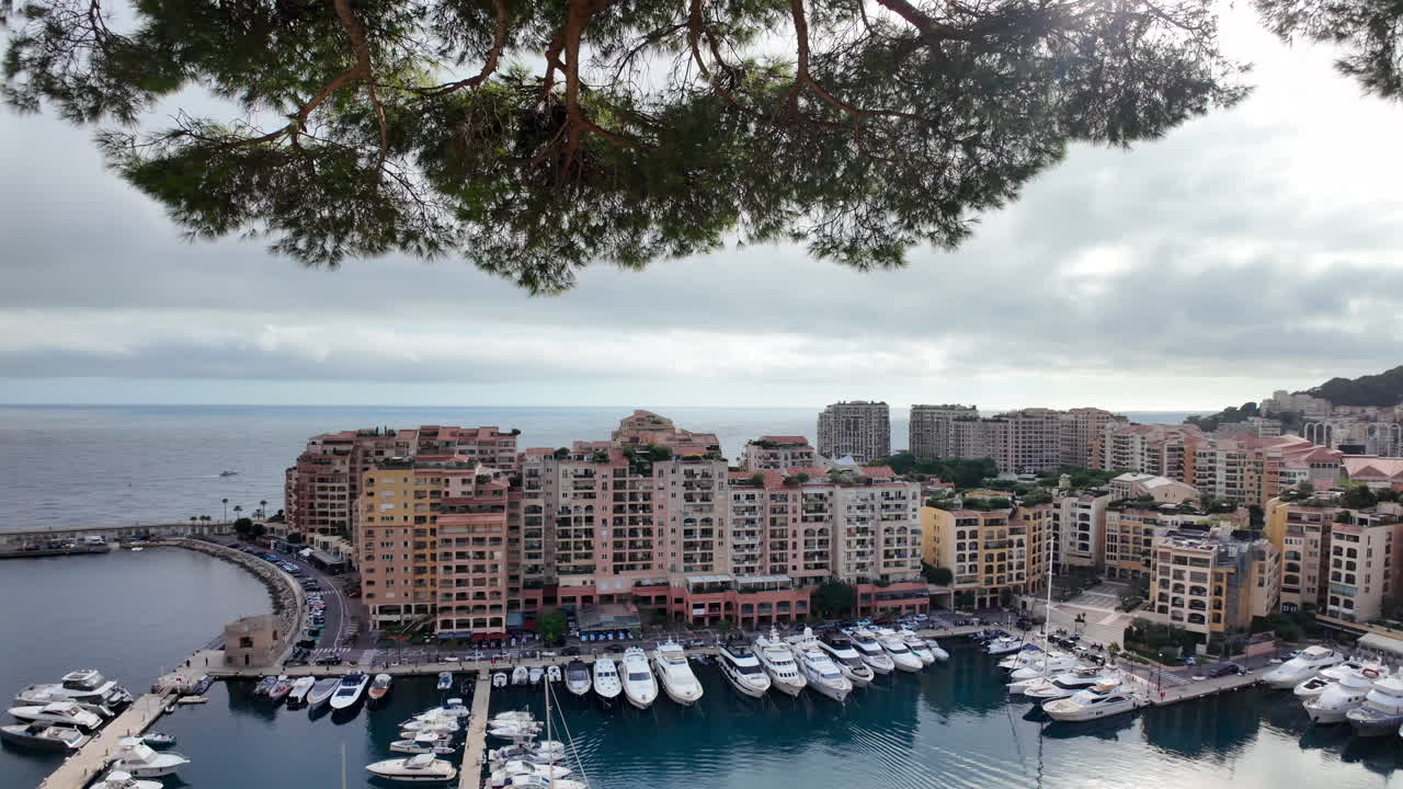Vista dall'alto di Port de Fontvieille a Monaco, con edifici colorati, yacht di lusso e il paesaggio montuoso circostante