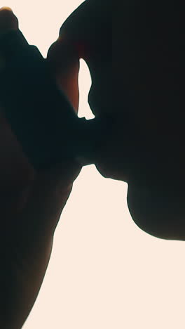 CU, Slow motion: silhouette of young person using inhaler to cure breathe disease against backlight in room extreme closeup