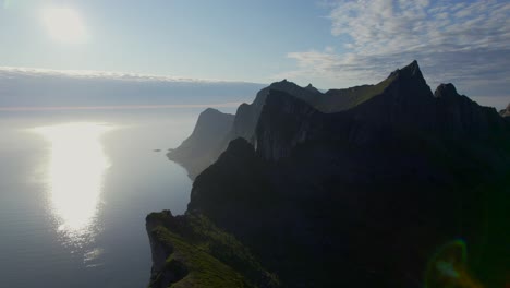 Reverse-dolly-shot-of-hesten-peak-in-silhouette-the-sun-shimmering-on-he-water-wand-peak-standing-on-the-dramatic-ridgeline