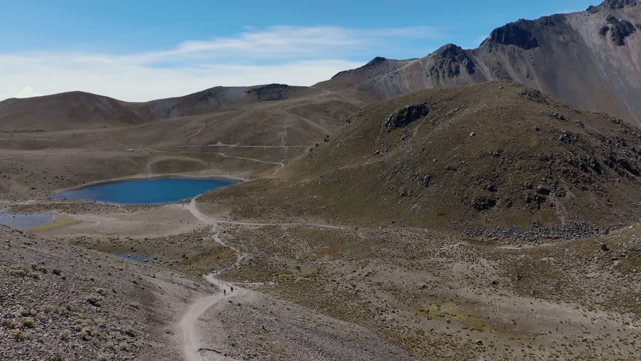 Laguna de la Luna inside Nevado de Toluca volcanic crater. Backward flight reveals people relaxing at Quetzal Pass after a difficult hike. Mexico