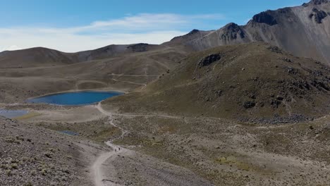 laguna de la luna inside nevado de toluca volcanic crater. backward flight reveals people relaxing at quetzal pass after a difficult hike. mexico
