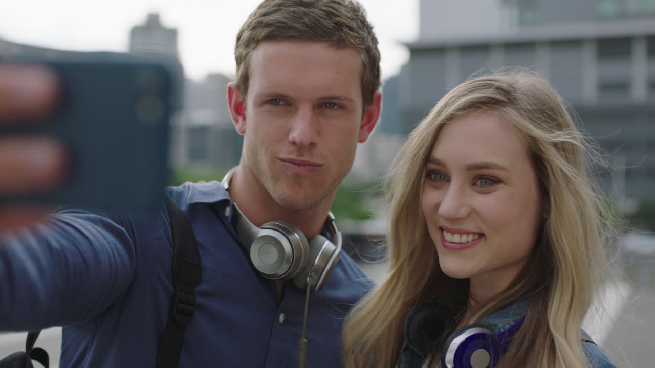 스마트 폰을 사용하여 사진을 찍고 도시 여행 라이프 스타일을 즐기는 행복한 젊은 백인 커플의 초상화