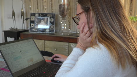 concentrated caucasian young blonde woman working from home with laptop