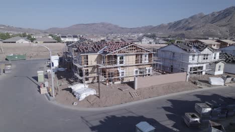 desde la distancia, un avión no tripulado inspecciona meticulosamente una casa parcialmente construida en un sitio de construcción, ofreciendo una visión integral del progreso en curso en el desarrollo residencial