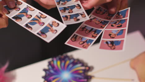 cerca de un grupo de amigos divirtiéndose mirando las impresiones de la cabina de fotos con accesorios 8