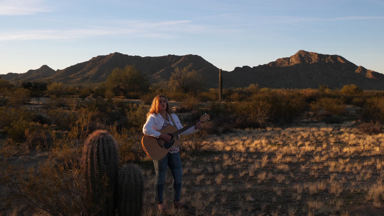 singing lady playing guitar under sunset, pan left long shot
