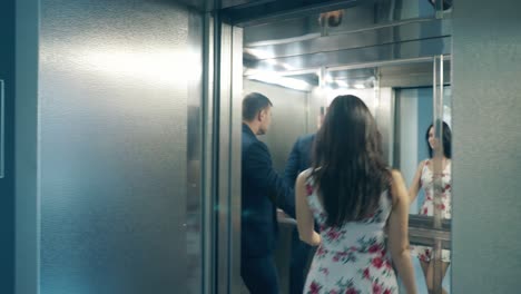 una joven pareja enamorada entra en un ascensor gris moderno y se abraza.