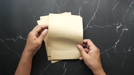 hands holding lined paper on a black marble table