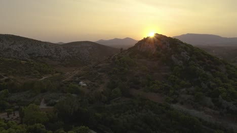 drone aerial view of a countryside rural landscape with the sun shinning on top of a mountain