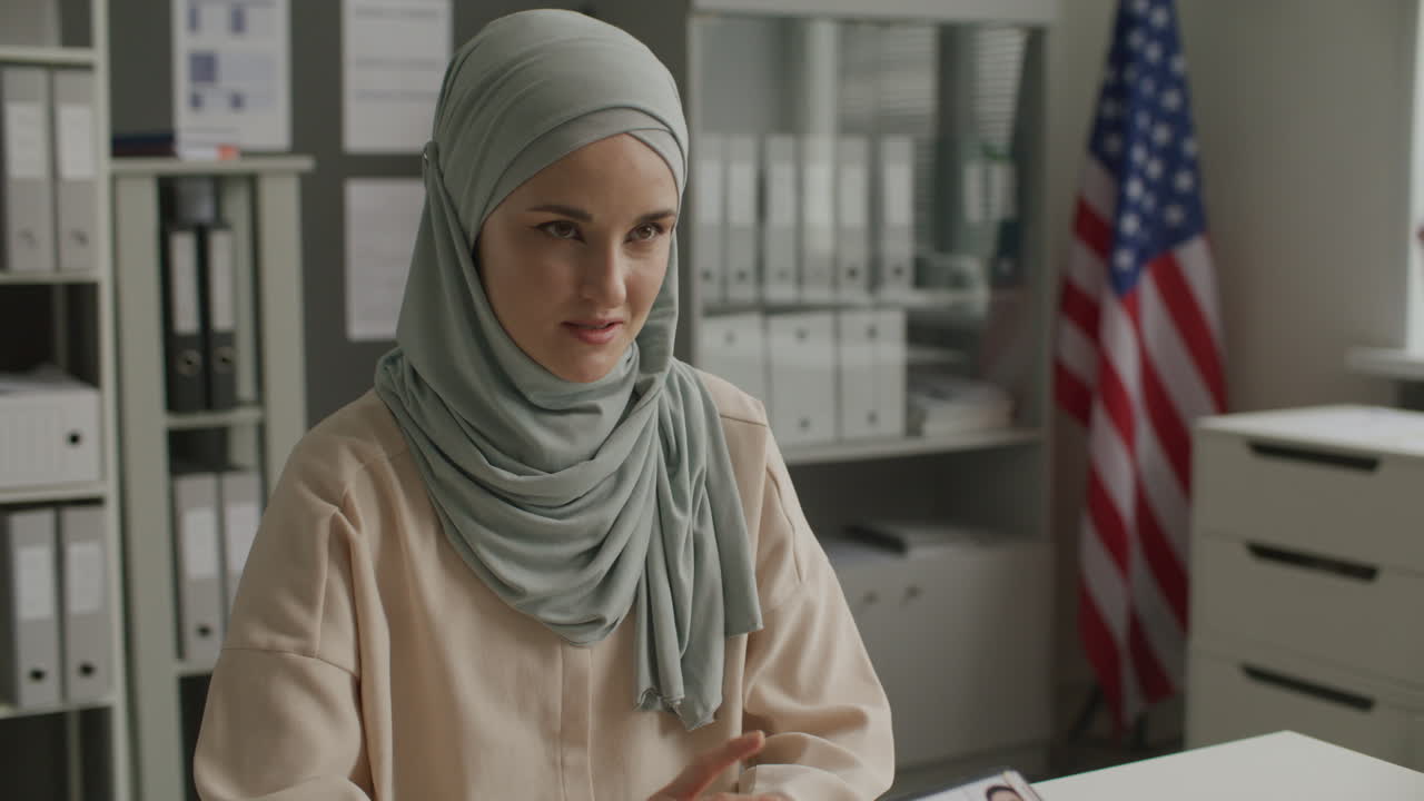 Funzionario consolare che conduce un colloquio per il visto con una donna con hijab presso l'Ambasciata degli Stati Uniti
