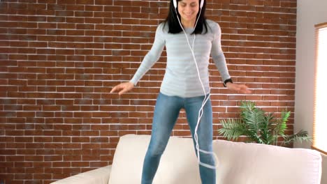 woman with headphones jumping on couch in living room