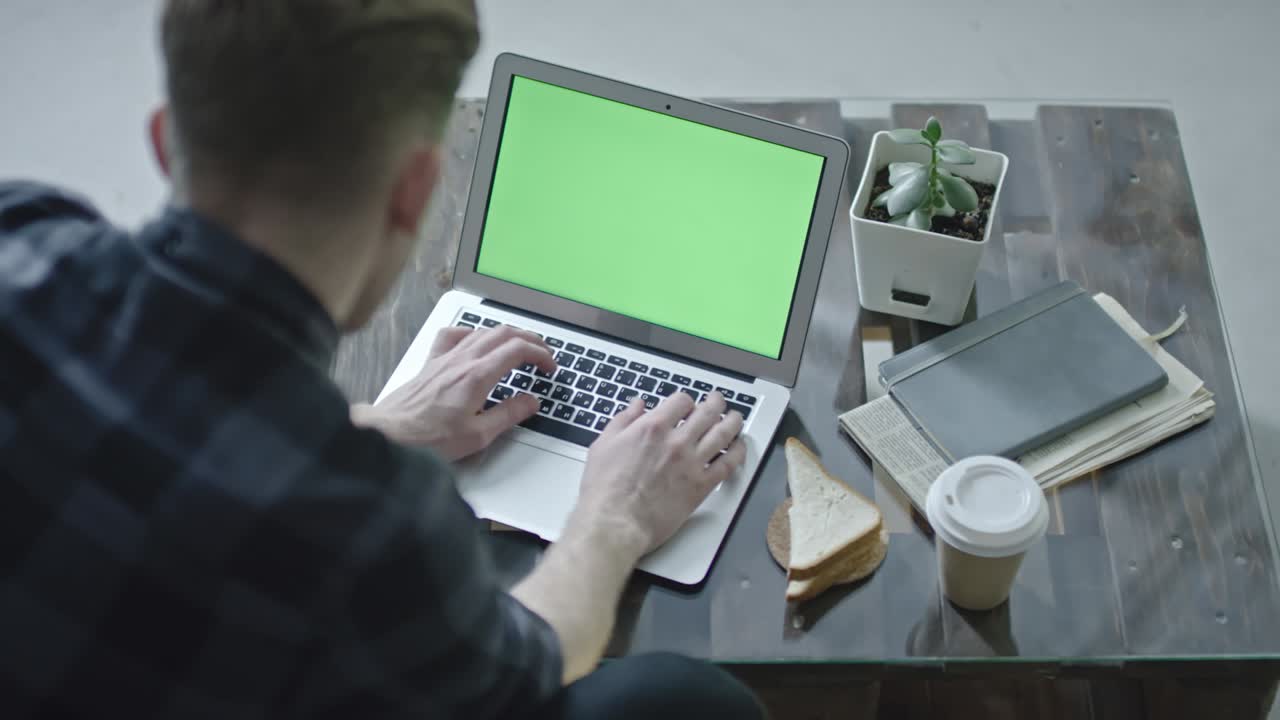 Man Working on Laptop with Chroma Key Screen