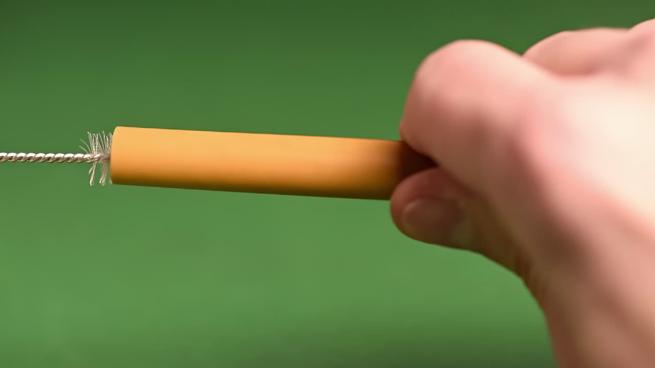 Bamboo straw cleaning with a brush with a green background