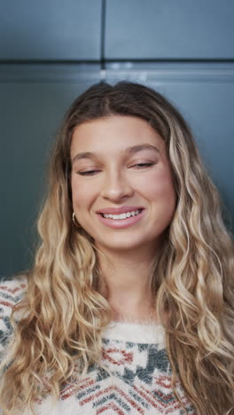 vertical video of portrait of happy biracial woman with blonde hair in kitchen at home, slow motion