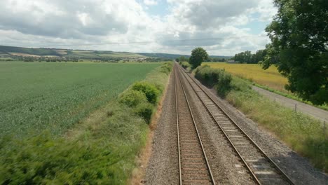 vista aérea de la escena rural británica con vías de tren, tierras agrícolas y campos verdes