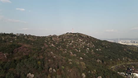 Aerial-drone-Nam-mountain-with-Seoul-Tower-in-foreground-and-city-in-background,-South-Korea