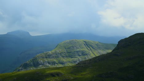 Thick-clouds-racing-over-covered-mountaintop-of-Scafell-with-cloud-shadows-moving-rapidly-between-valleys-and-over-mountainous-landscape