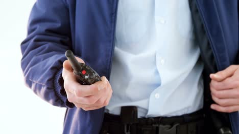 Mid-section-of-security-guard-holding-baton-and-walkie-talkie