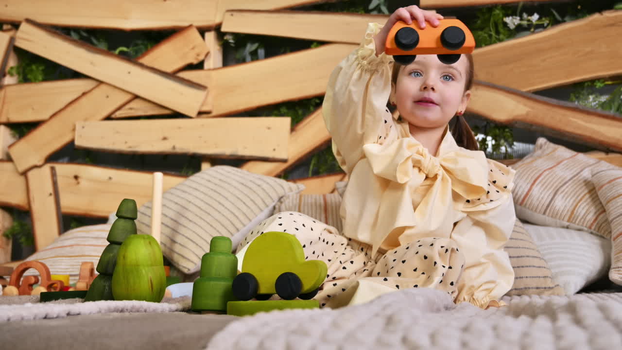 Little girl playing with a wooden rolling bus toy among others ecological toys. Sustainability concept