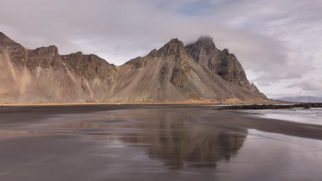 vestrahorn's jagged peaks mirrored on stokksnes’ black sand beach in iceland's coastal light stunning aerial view.