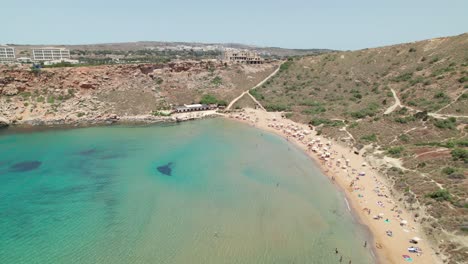 beach with tourists sunbathing and swimming in malta. mediterranean sea holiday destination