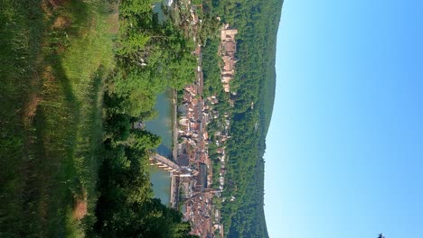 Hillside-vertical-view-of-Heidelberg-city-center-in-Germany-at-Neckar-river-with-castle-palace-and-Theodor-Bridge-in-a-long-wide-shot