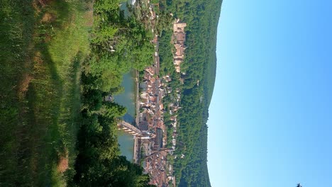 vista vertical de la ladera del centro de la ciudad de heidelberg en alemania en el río neckar con el palacio del castillo y el puente theodore en una toma larga y ancha