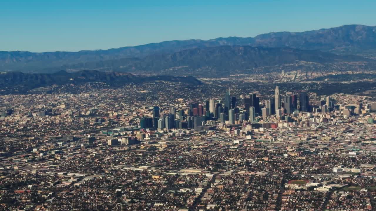 Un aereo della Delta Airlines scende sullo skyline di Los Angeles per l'atterraggio, offrendo una vista panoramica della città e dell'avvicinamento dell'aereo dal finestrino.