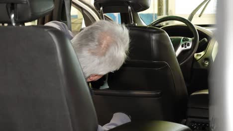 a vehicle detailer cleaning the back seat in a vehicle