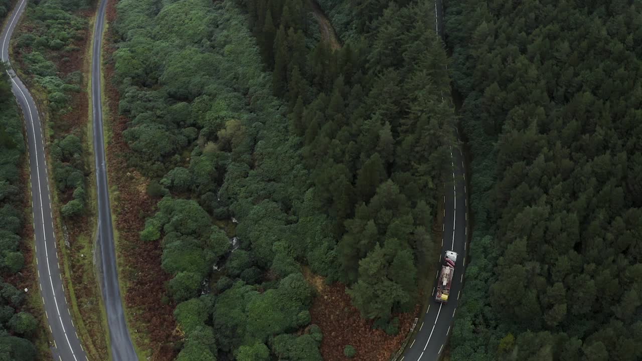 vista aérea de un camión conduciendo a través de un giro en forma de v en la carretera que conduce a una brecha en las montañas knockmealdown en clogheen, tipperary, irlanda