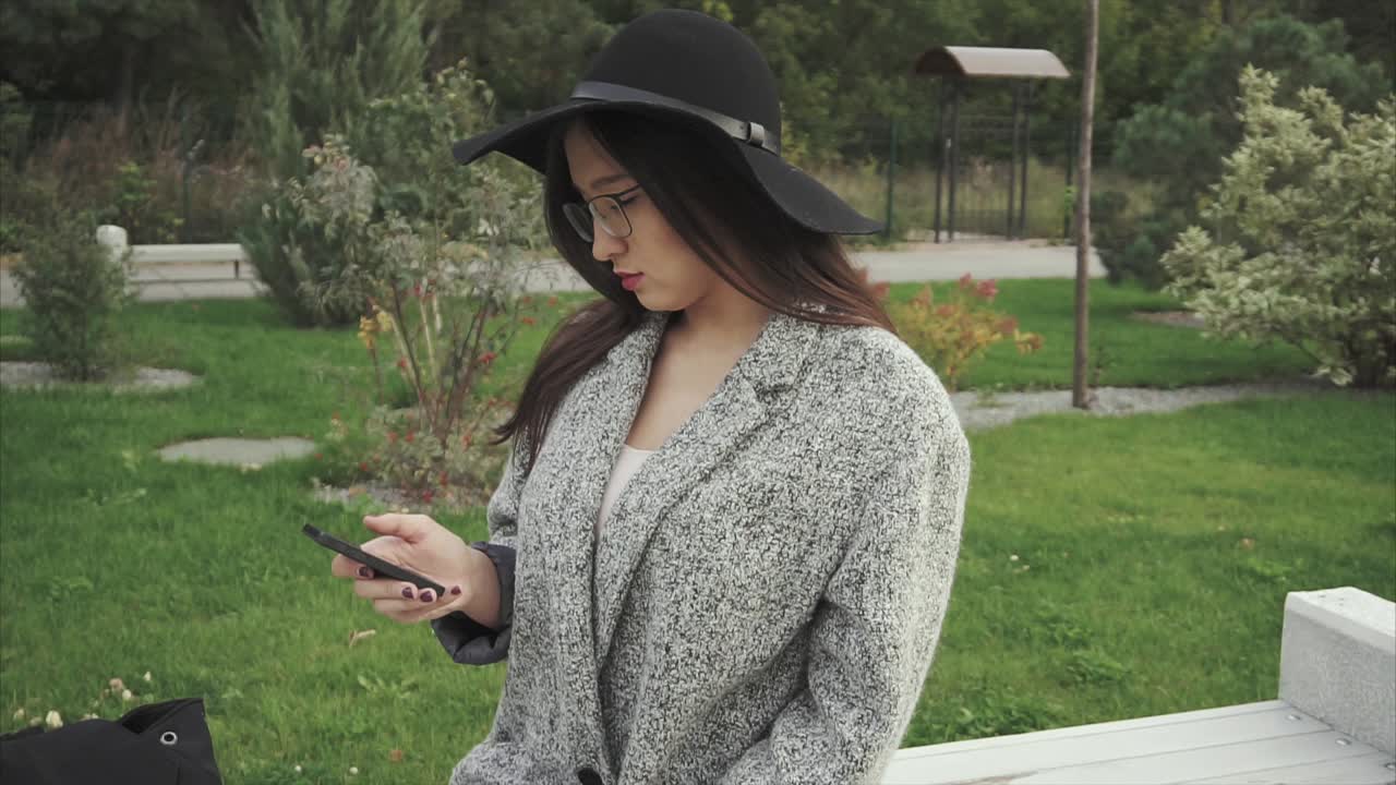 Young Woman Using Phone in a Park