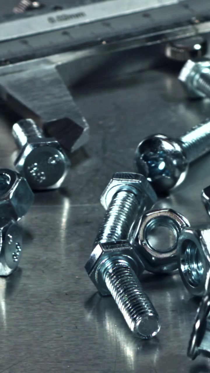 Rallentatore di dadi e bulloni metallici che cadono su una superficie metallica