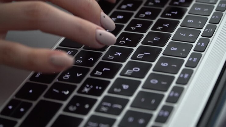Female hands press keys on the keyboard of a MacBook with a Russian layout
