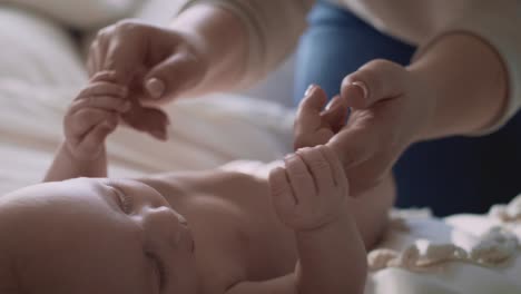 unrecognizable woman playing with her newborn baby lying on the bed