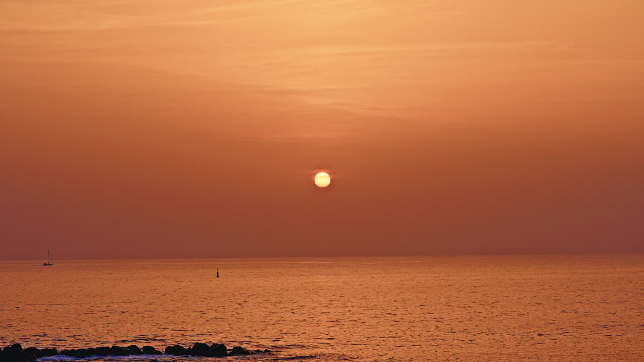 Warm tropical sunset at the sea. View of golden setting sun in the horizon.