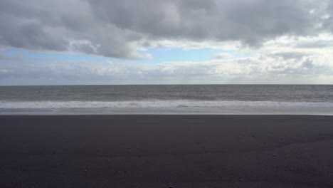 Schwarzer-Sandstrand-Mit-Brechenden-Wellen-Unter-Einem-Dramatischen-Wolkenhimmel-In-Island