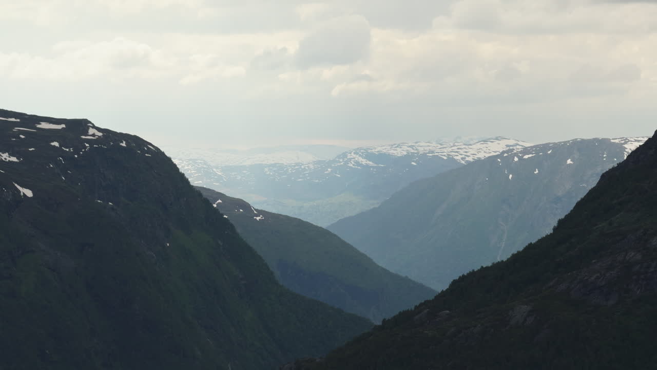 Mountain valley with snowy peaks, ominous weather.