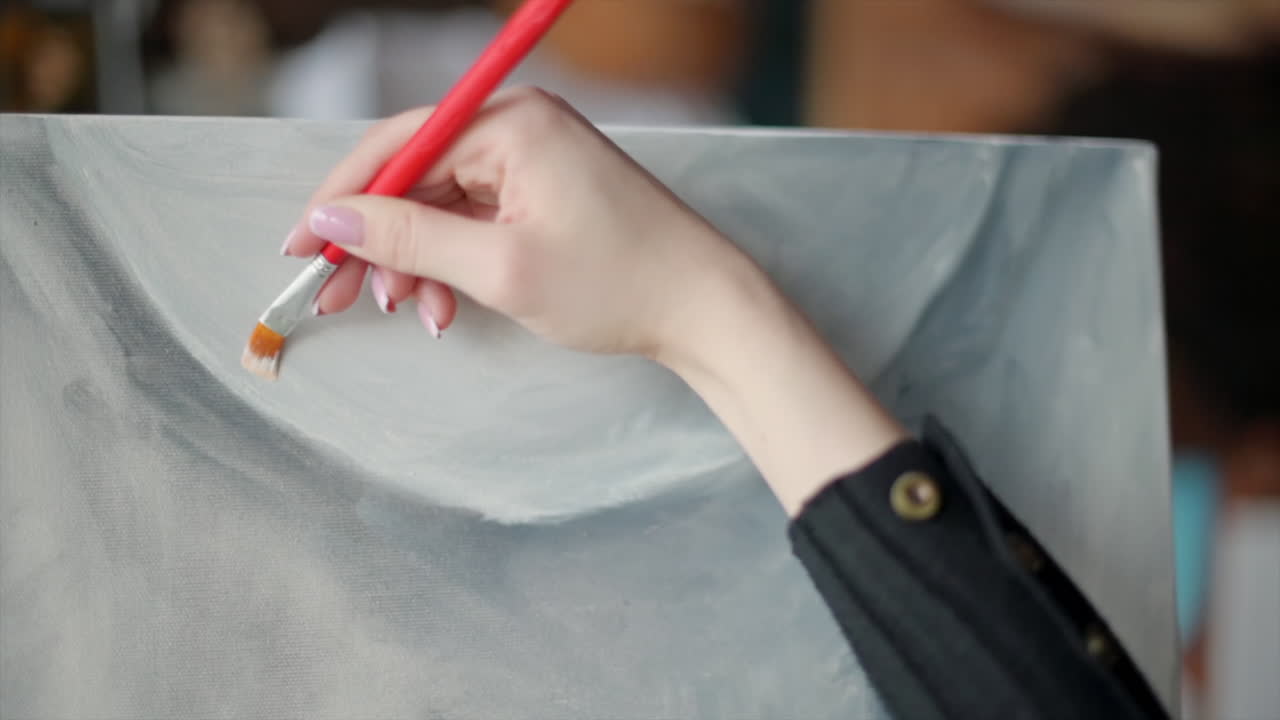 Close up of a woman painting a female body on a canvas at an art gallery workshop