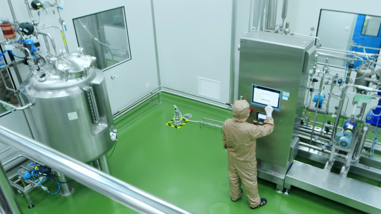 Technician or scientist in uniform work in high-tech stainless steel industrial processing tank control panel for automation, advanced industrial equipment production pharmaceutical biopharmaceuticals
