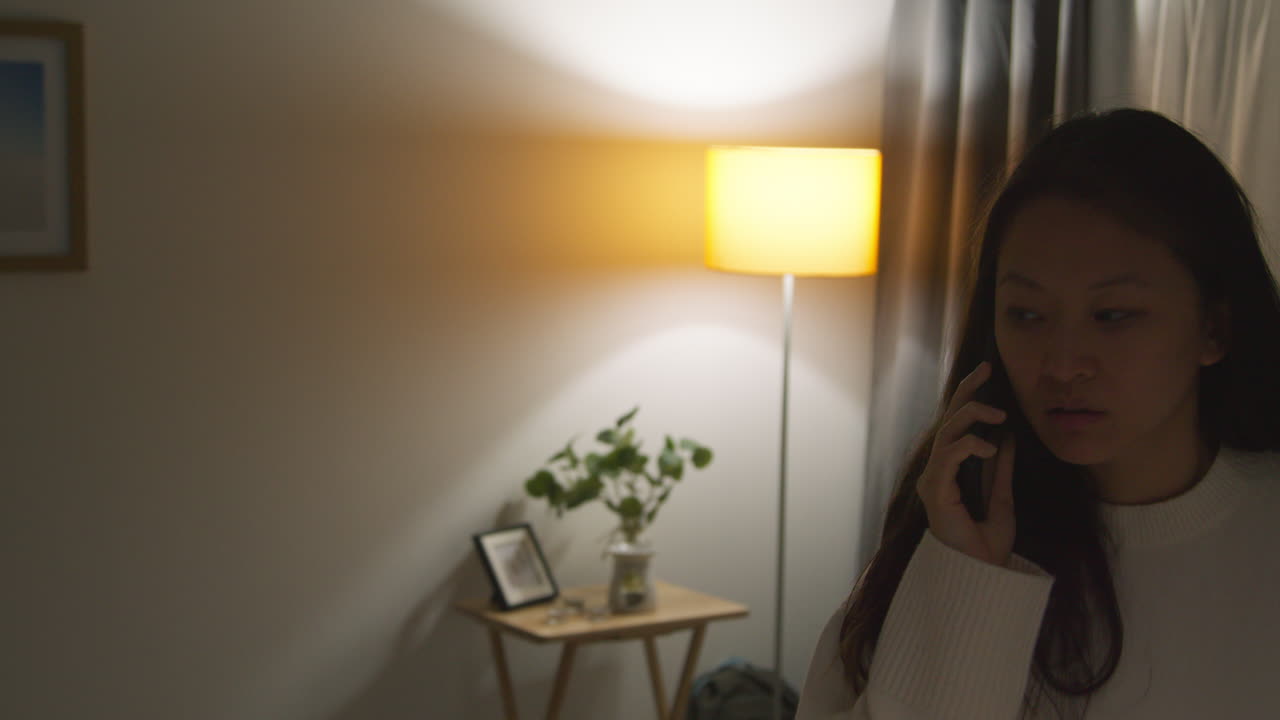 화가 나고 불안하거나 스트레스를 받는 여성이 집에서 저녁을 보내고 휴대 전화로 이야기하고 있습니다.