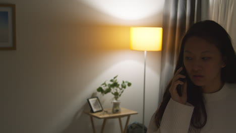 angry anxious or stressed woman spending evening at home in lounge talking on mobile phone 2