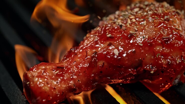 Marinated Drumstick Seasoned With Spice Mix Barbecuing On The Grill Among Flames in Macro and Slow Motion