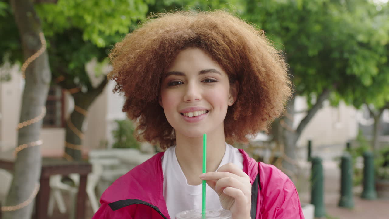 close up portrait of beautiful young teenage student girl smiling sipping juice beverage enjoying relaxed urban lifestyle in city background