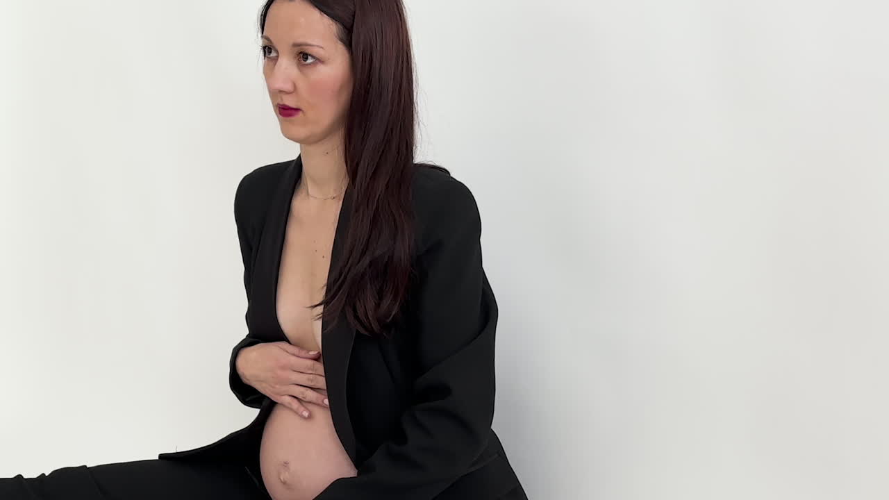 Brunette Pregnant Model Posing For A Photographer At A Pregnancy Photo Shoot Session.