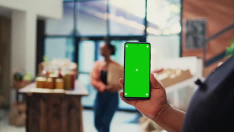 minorista sosteniendo un teléfono móvil con diseño de pantalla verde