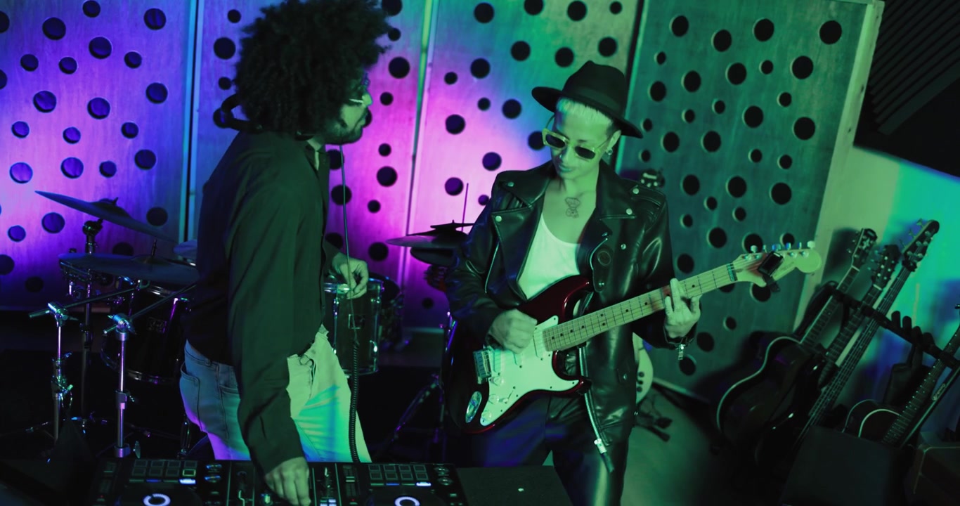 Musicians Playing Electric Guitar and DJ Mixer in a Neon Lit Studio