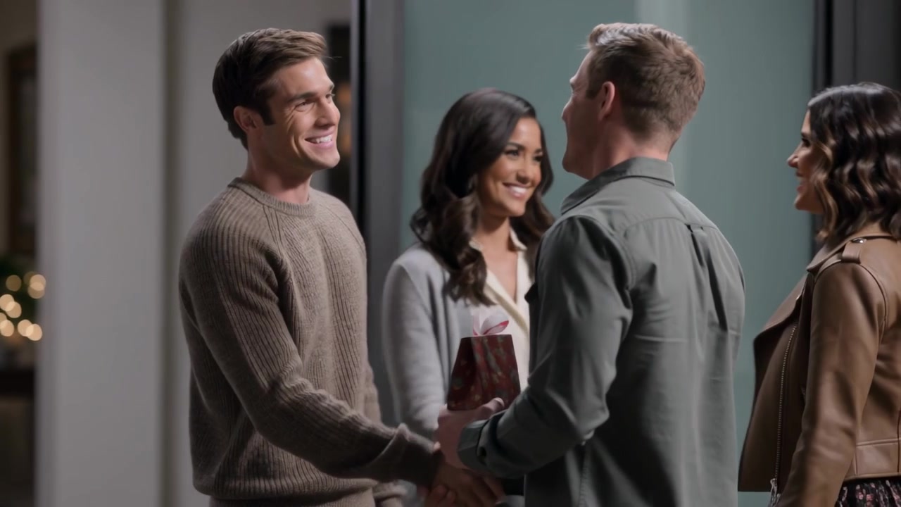Arriving, holding glass door, brown-sweatered man shaking hands with host and offering wrapped gift
