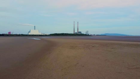 Un-Video-De-Dron-Bajo-De-La-Playa-Vacía-En-Sandymount-Strand-Con-El-Incinerador-De-La-Ciudad-De-Dublín-Y-Las-Chimeneas-Poolbeg